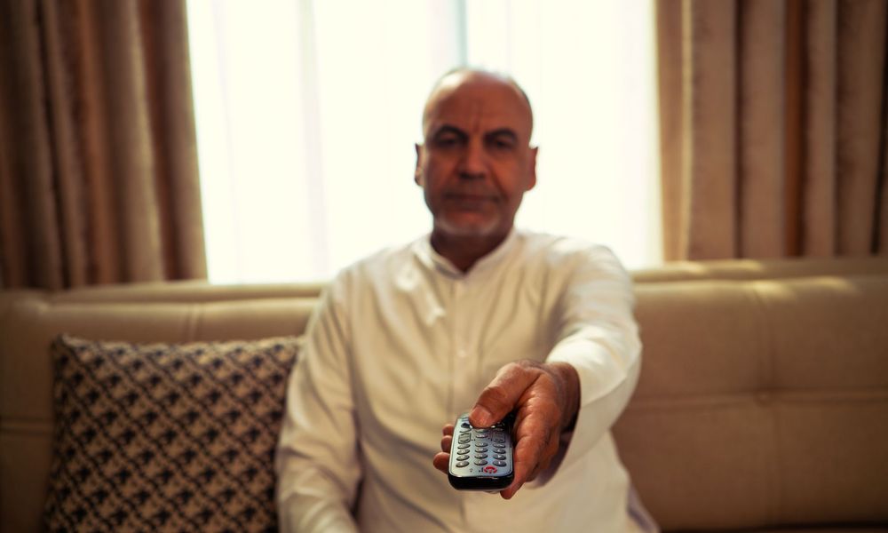 Personne détendue avec sa télécommande sur le canapé
